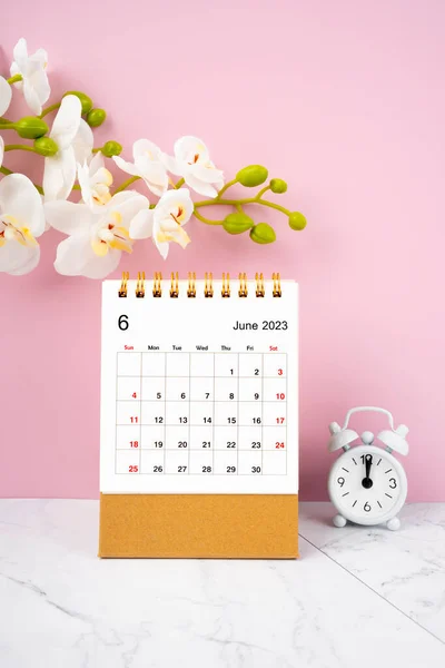 2023年6月ピンクの背景に白い蘭とカレンダーデスクとアラーム色 — ストック写真