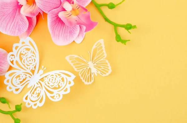 蝶紙黄色の背景にピンク色の蘭とカット — ストック写真