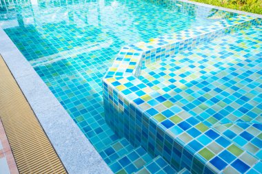 Macro from Swimming pool with clear blue water in a garden area, surrounded by plants