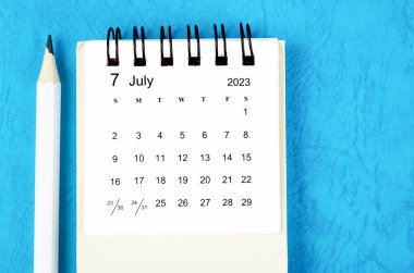 2023 Temmuz Masa takvimi mavi arka planda kalem ile 2023.