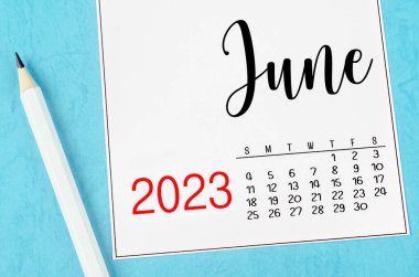 2023 Haziran ayının masa takvimi mavi arka planda kalemle..