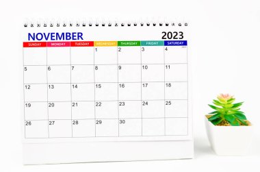 2023 Kasım ayının masa takvimi. Beyaz arka planda bitki saksısı izole edilmiş..