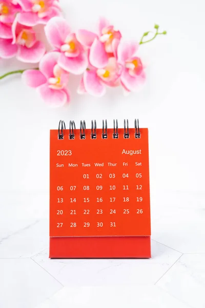 Red calendar August 2023. Desk calendar for year 2023 and pink orchid.