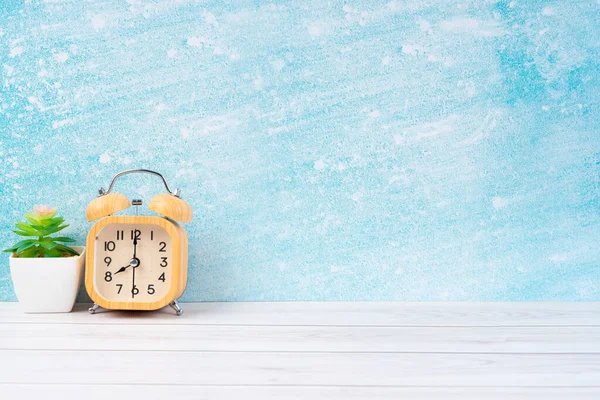 木製の目覚まし時計とあなたのデザインのためのコピースペースと青の木製の床に植物ポット — ストック写真