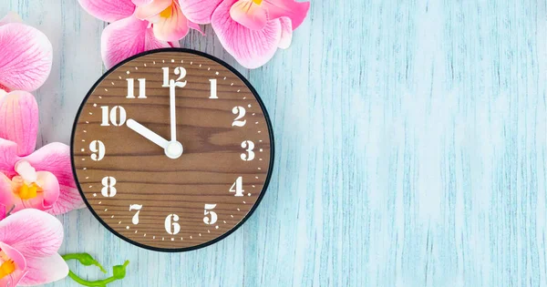 木製時計とピンクの縞蘭の花の青い木製の背景に — ストック写真