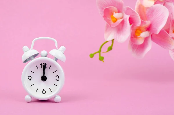 白い目覚まし時計とピンクの縞模様の蘭の花の甘い背景 — ストック写真