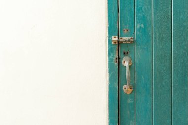 Kapalı asma kilit yeşil renkli ahşap kapıda ve duvarda asılı..