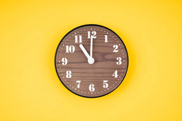黄色の背景に11時位置にレトロな木製の時計 — ストック写真