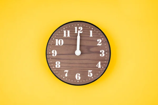 黄色の背景に12時位置にレトロな木製の時計 — ストック写真