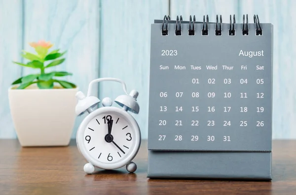 stock image August 2023 Monthly desk calendar for 2023 year with alarm clock on blue wooden background.