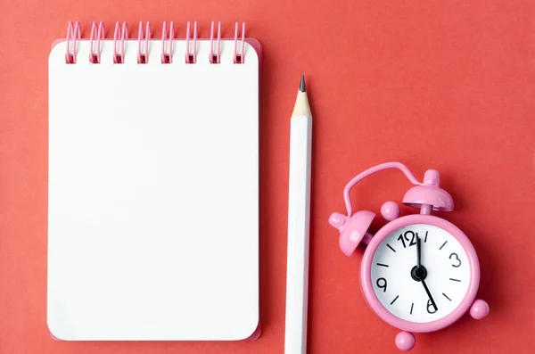 ブランクオープン日記と赤い色の背景に鉛筆と目覚まし時計 — ストック写真