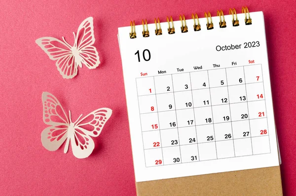 October 2023 calendar desk for the organizer to plan and reminder with butterfly paer on red background.