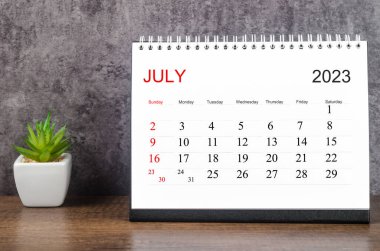 2023 Temmuz Masa takvimi ahşap masa üzerinde küçük bir bitki ile 2023 yılı.