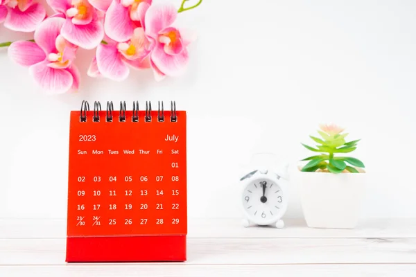 赤い暦2023年7月 2023年のデスクカレンダーと木製の背景のピンクの蘭 — ストック写真