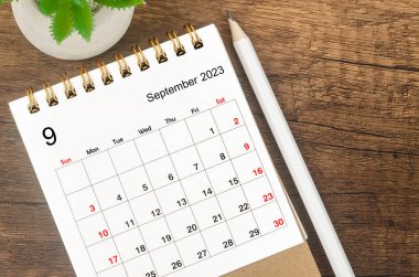 2023 Eylül masa takvimi için ahşap arka planda kalem.