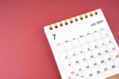 Kırmızı arkaplanda organizatörün planlayıp hatırlatması için Temmuz 2023 takvim masası.