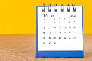 2023 yılının Ekim ayının masa takvimi sarı arka planda..