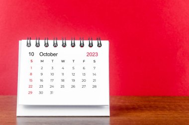 2023 yılının Ekim ayının masa takvimi kırmızı arka planda.