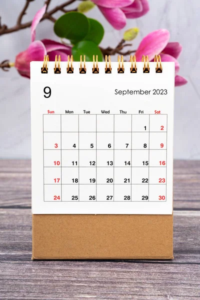 2023年9月桌上日历和木制背景的白色粉红木兰花 — 图库照片