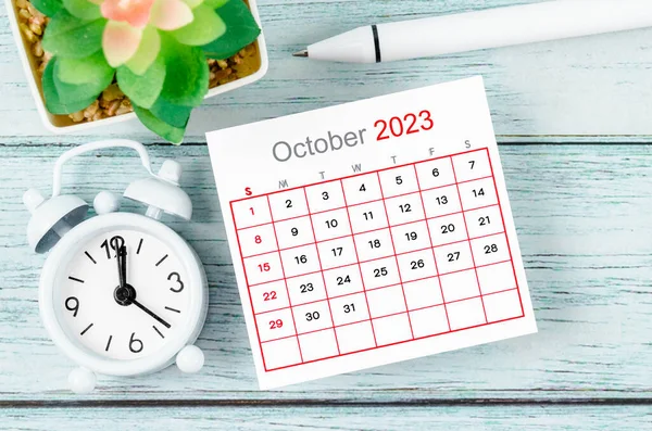 2023年10月カレンダー年と青い木製の背景にペン付き目覚まし時計 — ストック写真