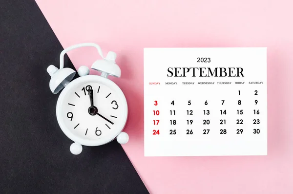 2023年9月ピンク色の背景に目覚まし時計と毎月の暦年 — ストック写真