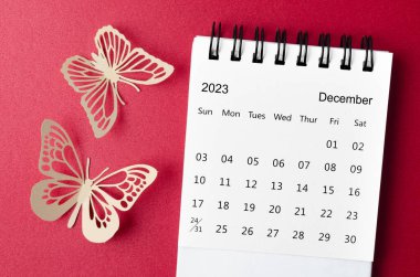 Aralık 2023 Kırmızı zemin üzerinde paer kelebek ile planlama ve hatırlatma için düzenleyici için masa takvimi.