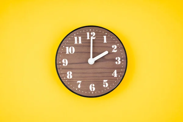 レトロな木製時計で2時位置に黄色の背景色 — ストック写真