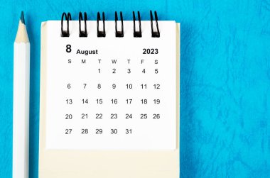 2023 Ağustos ayının masa takvimi mavi arka planda kalemle..