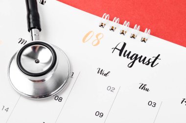 Stetoskop tıbbi ve Ağustos 2023 masa takvimi kırmızı arka planda, sağlıklı kavramları kontrol etmek için takvim.