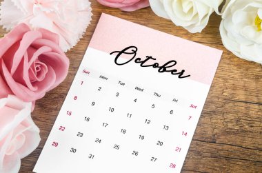 2023 Ekim ayının takvimi. Ahşap arka planda pembe gül..