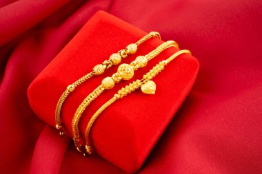 Many gold bracelet and red velvet box on the red silk background display clipart