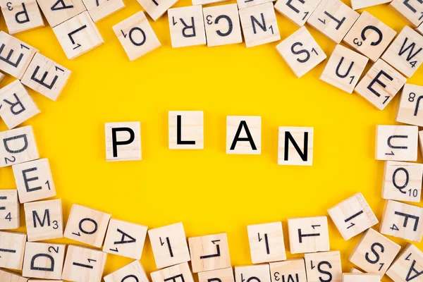 Ahşap küplerle ilgili plan kelimesi. Sarı zemin üzerinde harf yığını olan alfabe blokları.