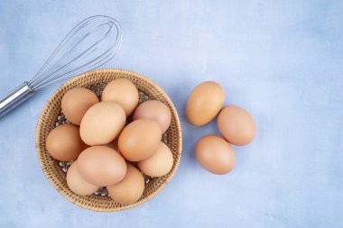 Mavi ahşap arka planda sepetteki organik tavuk yumurtalarının üst görüntüsü.