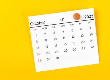 Ekim 2023 ve sarı arkaplanda ahşap raptiye.