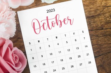 2023 Ekim ayının takvimi. Ahşap arka planda pembe gül..
