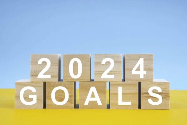 Wooden cubes 2024 GOALS on yellow and blue background. Planning and goals concepts on 2024 year.