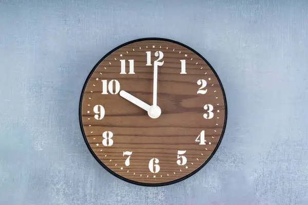 青いセメントの壁の真ん中に置かれたブラウンの木製時計 — ストック写真