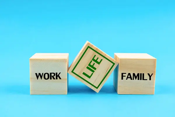 Wooden blocks with the words FAMILY, WORK and LIFE on blue background.