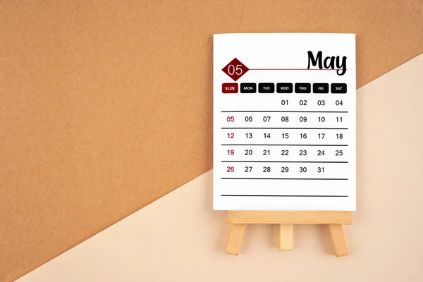 May 2024 calendar page on brown background.