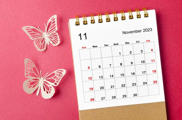 November 2023 calendar desk for the organizer to plan and reminder with butterfly paer on red background.