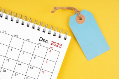 Aralık 2023 Sarı zemin üzerinde boş fiyat etiketi olan masa takvimi.