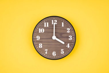 Sarı arkaplanda saat 4 yönünde tahta saat var..