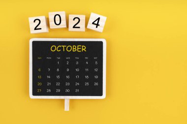 Ekim 2024 için sarı arkaplan üzerinde kopya alanı olan siyah karatahta takvimi.