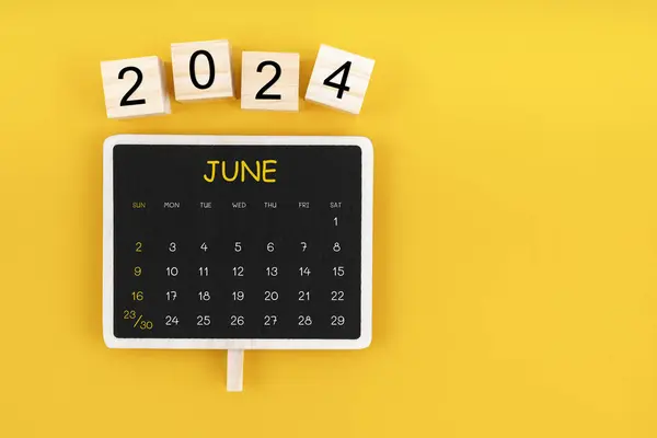 Calendar for June 2024 in black chalkboard with copy space on a yellow color background.