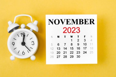 2023 Kasım ayının takvimi. Sarı arka planda alarm saati var..