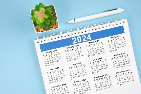 Hello 2024 calendar. 12 months desk calendar 2024 with pen on blue background.