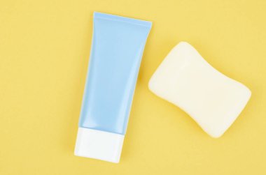 Üst görünüm mavi sıkma şişe plastik tüp ve bitki sabunu sarı zemin üzerinde ilaç veya kozmetik markalaşma için.