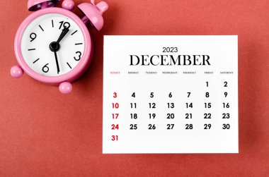 Aralık 2023 Aylık takvim yılı kırmızı arkaplan üzerindeki alarm saati.