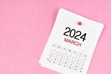 Mart 2024 takvim sayfası ve pembe renk arkaplanındaki ahşap düğme.