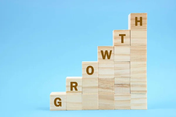 Growth word on wooden blocks staircase on blue color background.